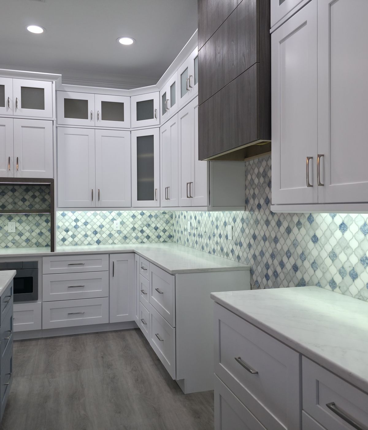 White kitchen cabinets with blue tile backsplash, finished by Renovari