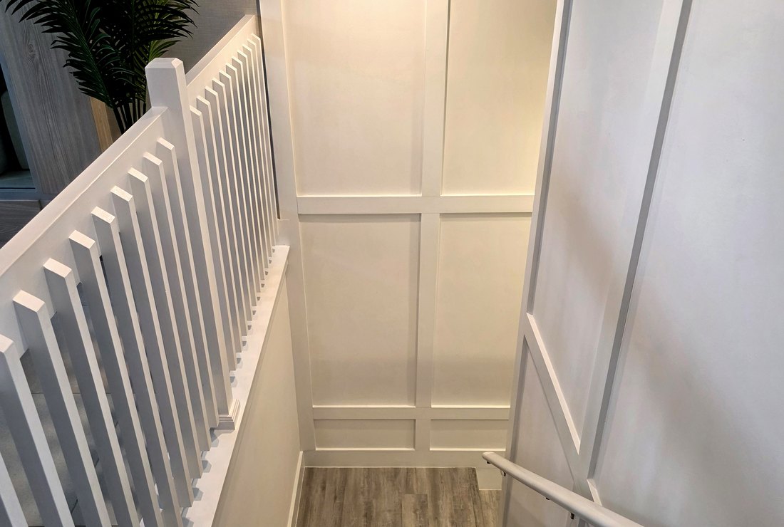 Staircase walls, paneling and trim painted white by Renovari
